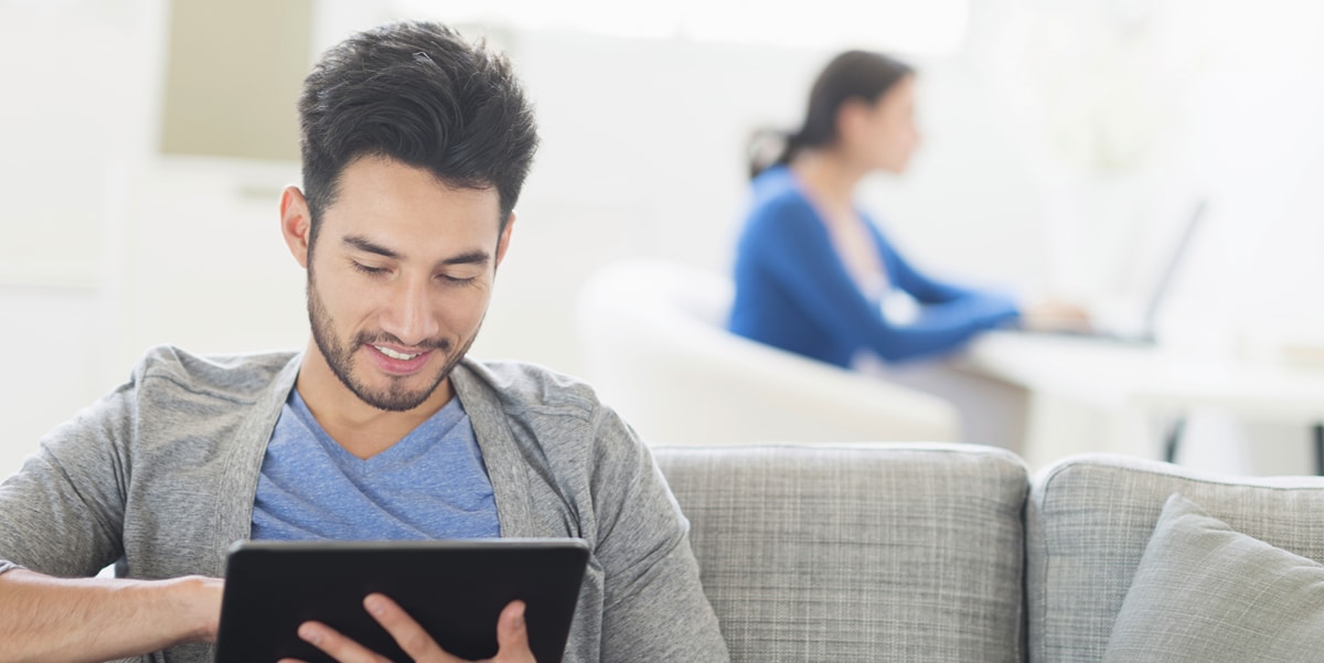 Man sitting on a couch looking at a tablet